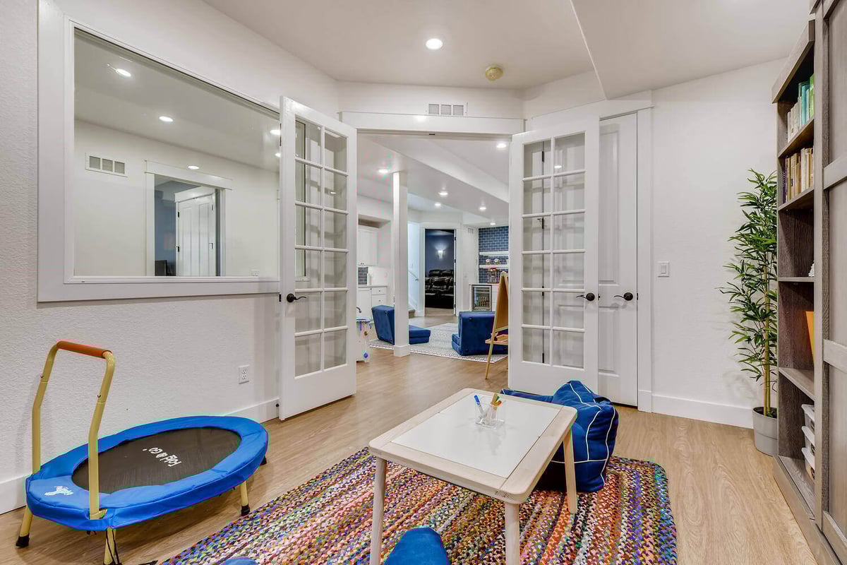 Lower-level office with glass doors and playroom area, Denver, CO by Sheffield Homes