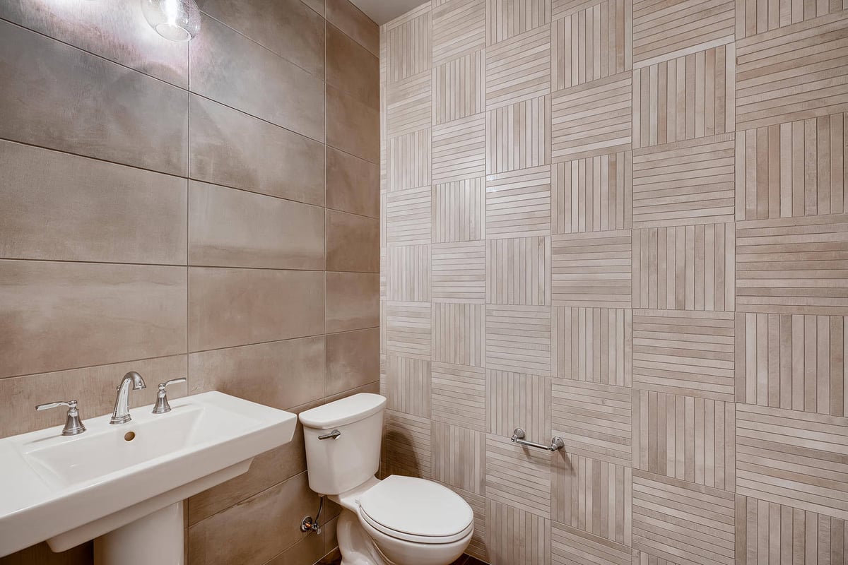 Elegant powder room with tiled walls in a custom home by Sheffield Homes in Arvada, CO