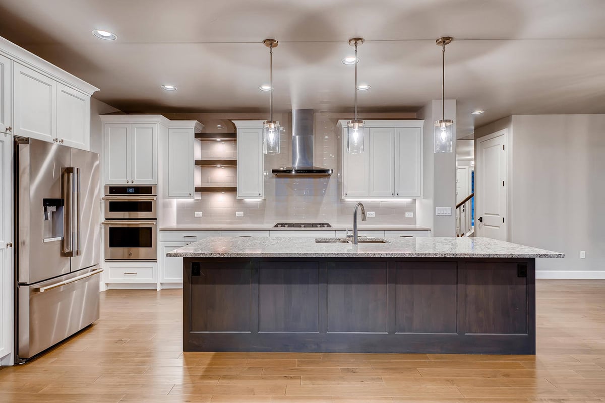 Gourmet kitchen with stainless steel refrigerator and double ovens in a custom home by Sheffield Homes in Arvada, CO