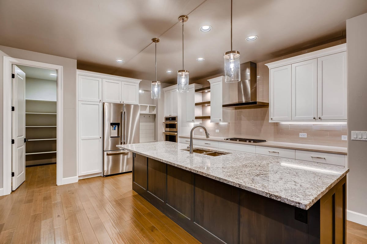 Modern kitchen with large island and pendant lights in a custom home by Sheffield Homes in Arvada, CO