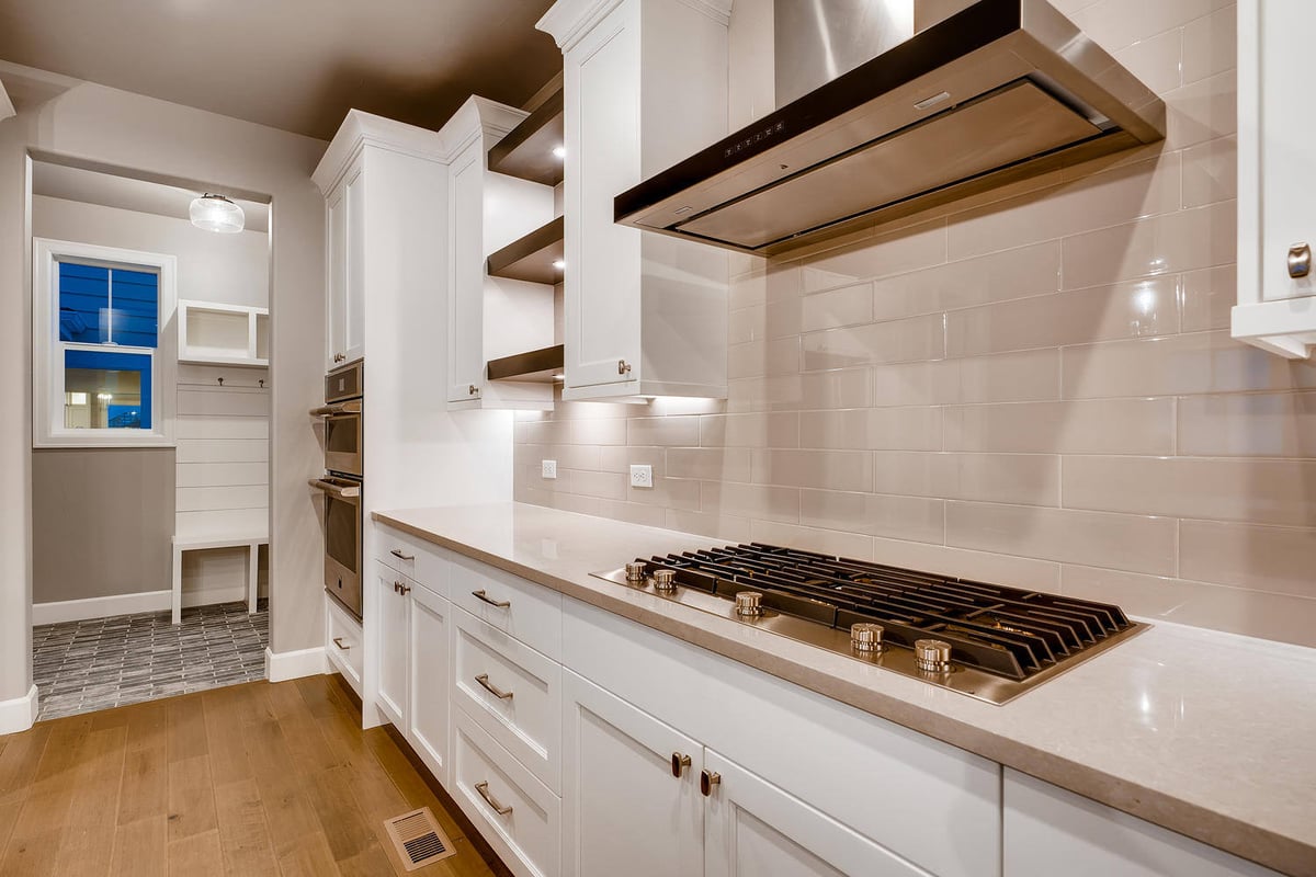 Modern kitchen with stainless steel range hood and gas stovetop in a custom home by Sheffield Homes in Arvada, CO