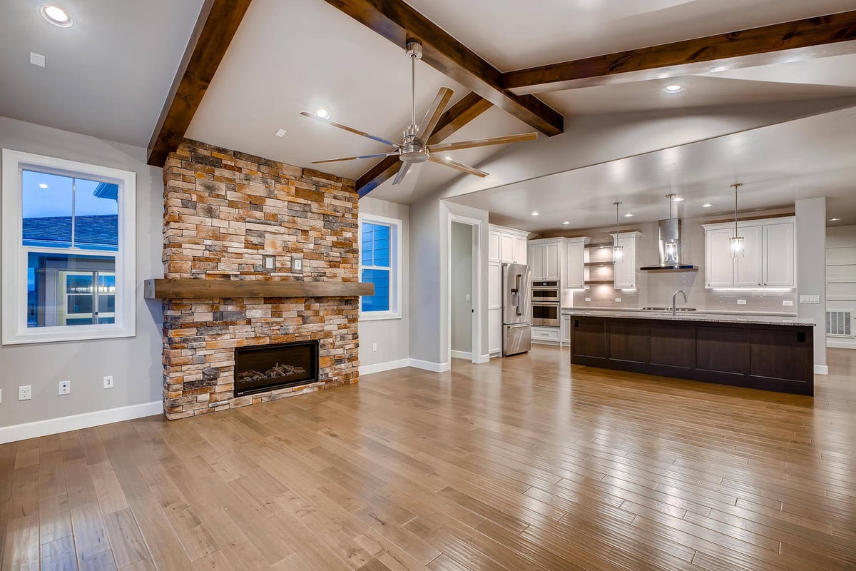 Open-concept living room with stone fireplace in a custom home by Sheffield Homes in Arvada, CO
