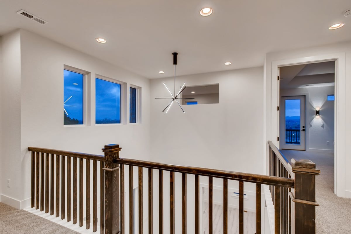 Bright upstairs landing with modern light fixture and wood railing in Arvada, CO home