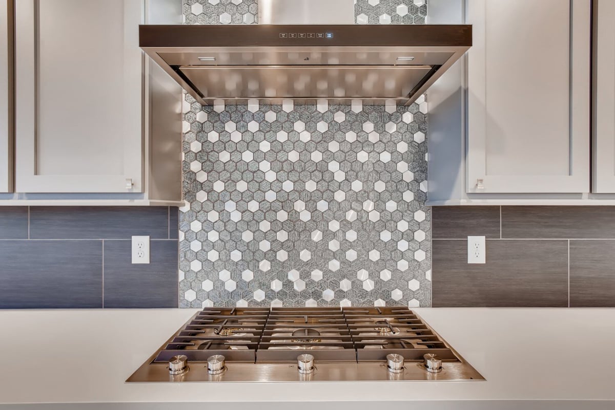 Close-up of a modern hexagonal tile backsplash and stainless steel range in Arvada, CO kitchen