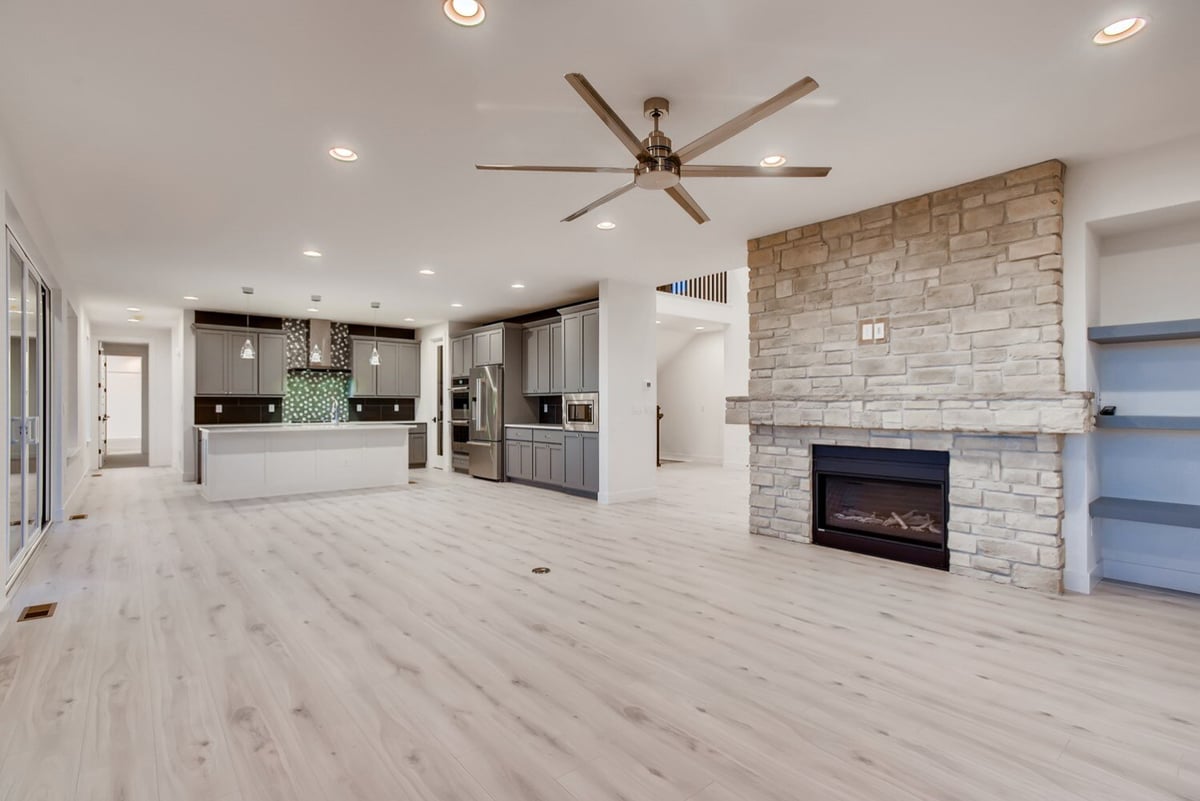 Custom living room by Sheffield Homes in Arvada, CO, featuring a stone fireplace and large windows