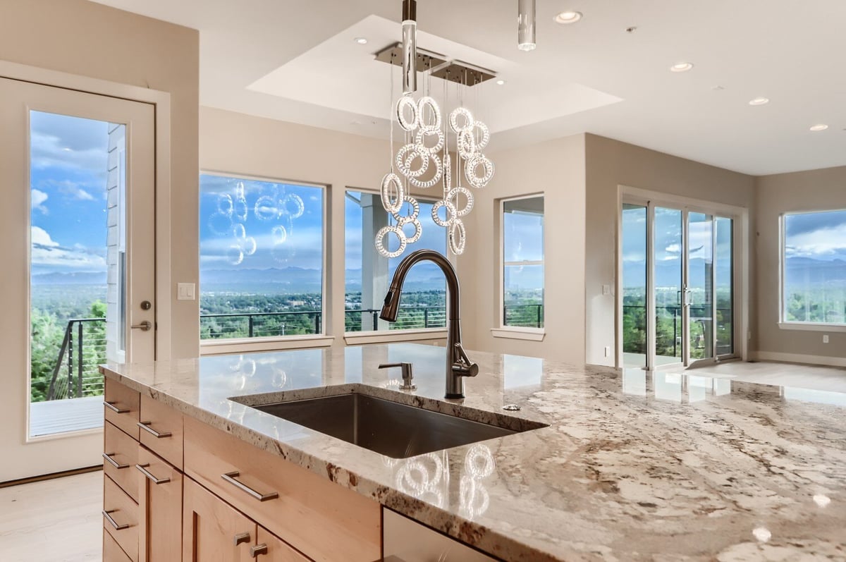 Close-up of a modern kitchen island with granite countertop and elegant lighting in a Sheffield Homes project in Arvada, CO