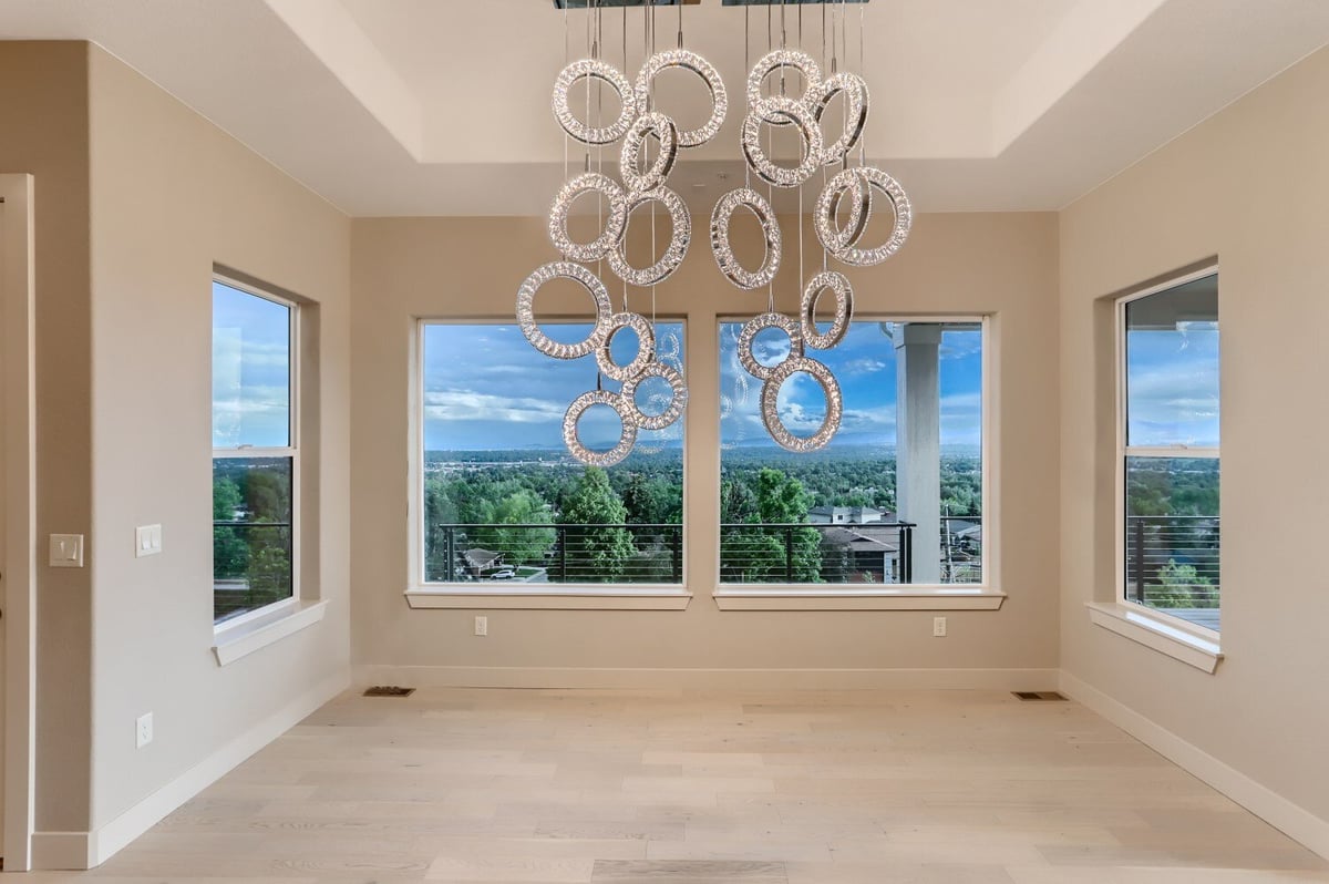 Elegant dining room with modern chandelier and large windows in a Sheffield Homes custom home in Arvada, CO