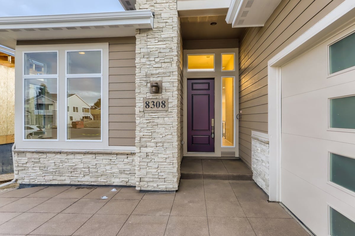 Front entryway of a custom home with stone accents and a purple door by Sheffield Homes in Arvada, CO