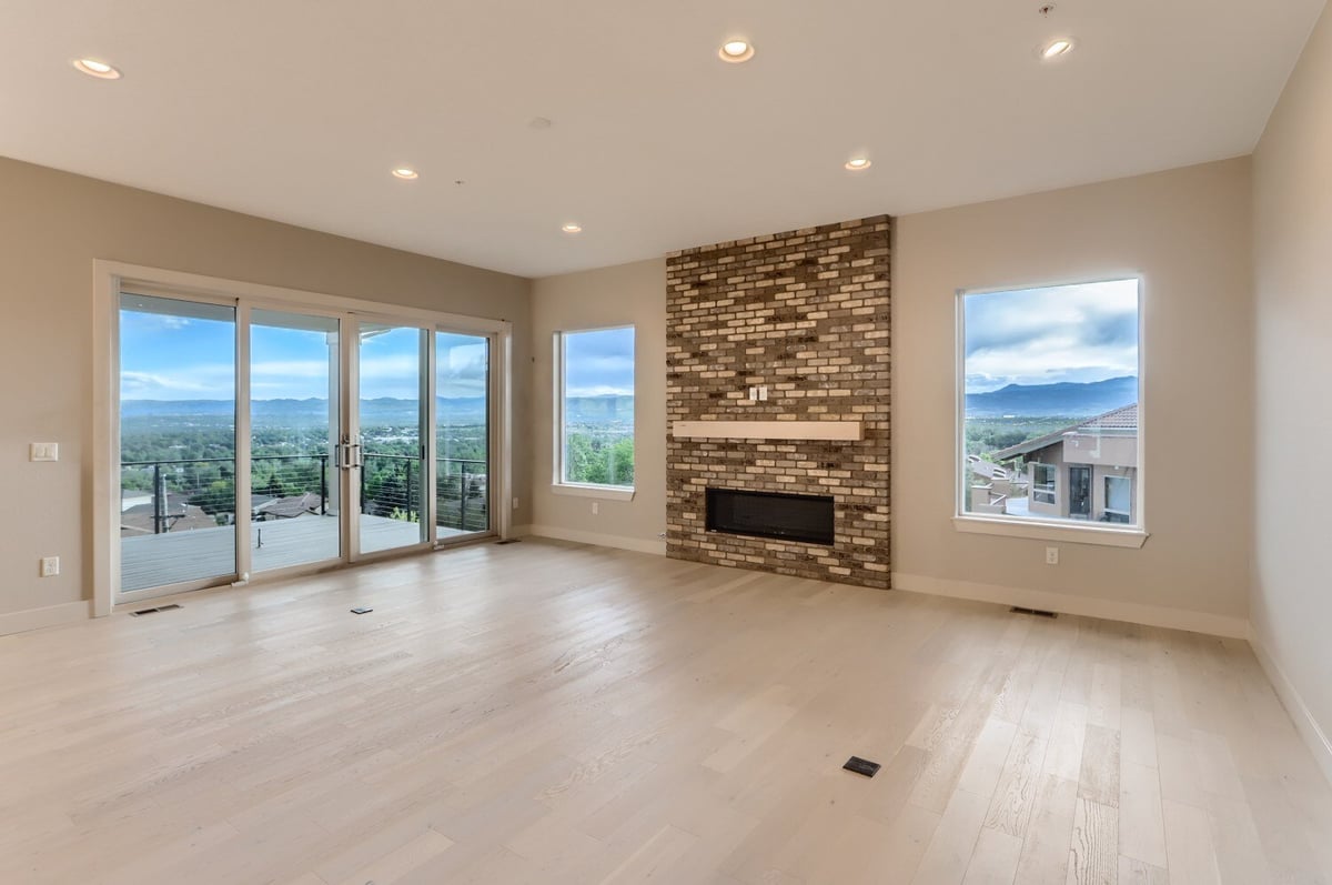 Living room with stone fireplace and floor-to-ceiling windows in a Sheffield Homes custom home in Arvada, CO