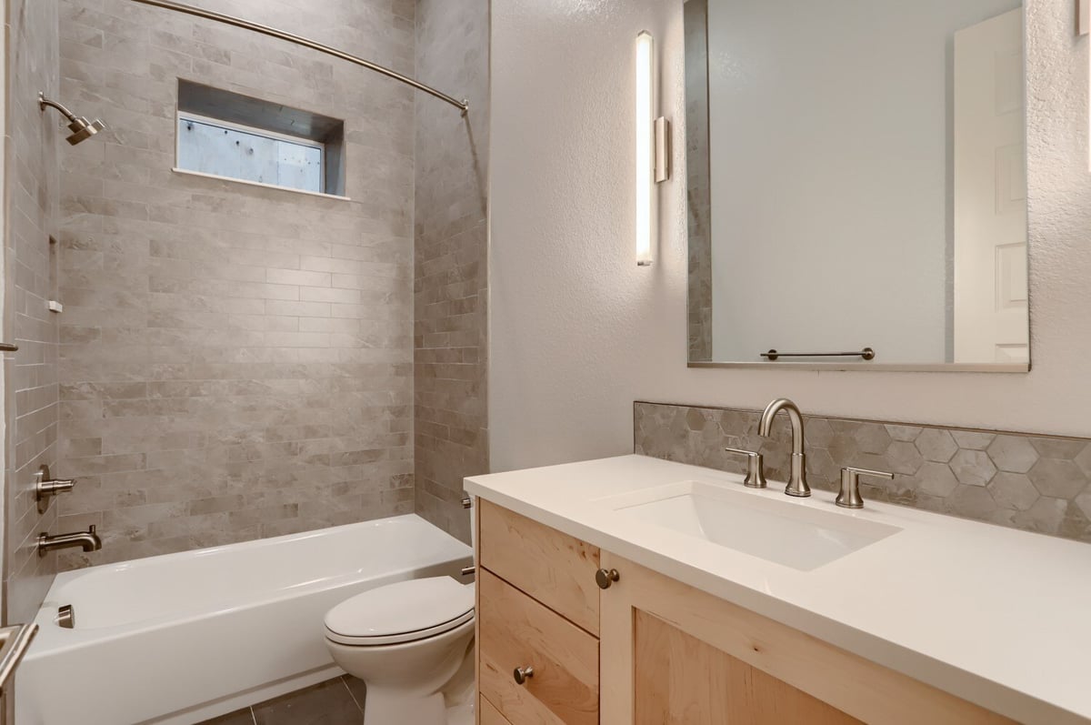 Modern bathroom with tiled shower and wood cabinetry in a Sheffield Homes custom home in Arvada, CO