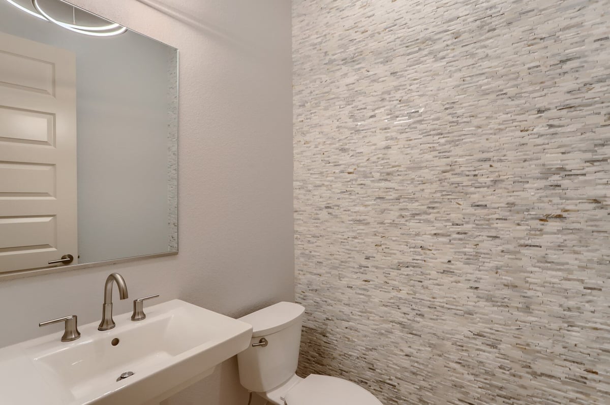 Modern powder room with stone tile wall and sleek fixtures in a custom home by Sheffield Homes in Arvada, CO