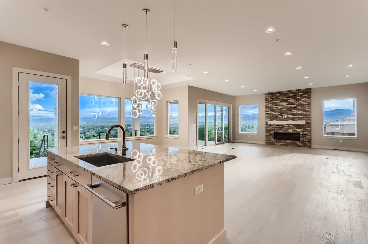 Open kitchen and living area with island and modern lighting in a custom home by Sheffield Homes in Arvada, CO