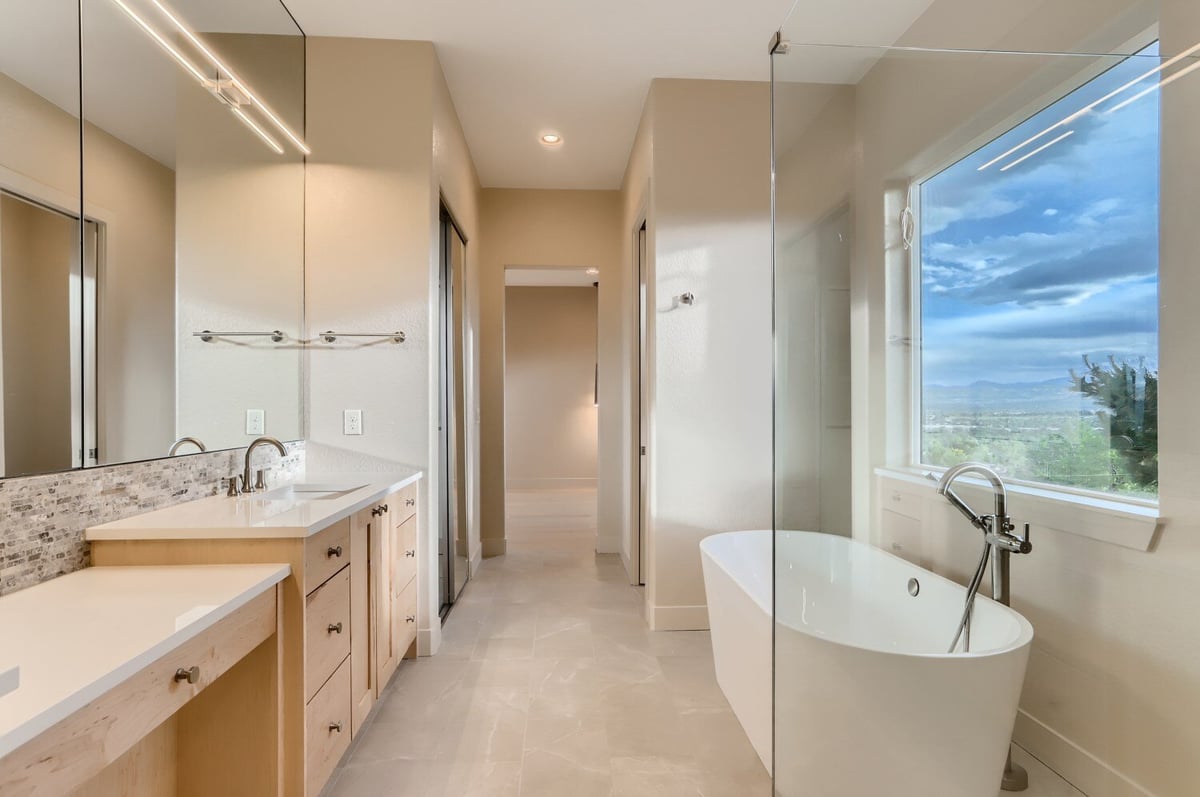 Primary bathroom with dual vanities and freestanding tub offering mountain views by Sheffield Homes in Arvada, CO