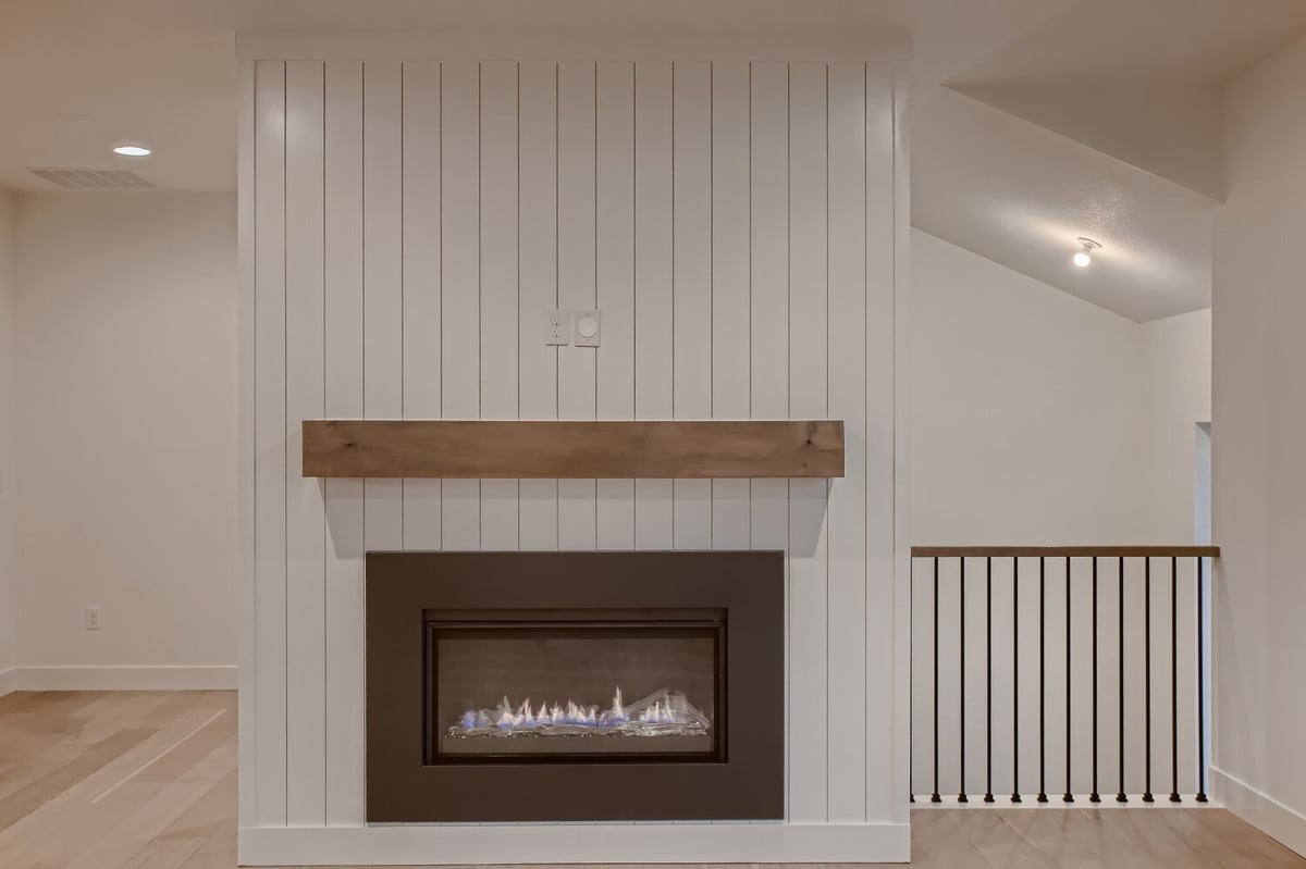 A fireplace with an elegantly designed back wall and a sleek railing behind in a custom home by Sheffield Homes, Arvada, CO