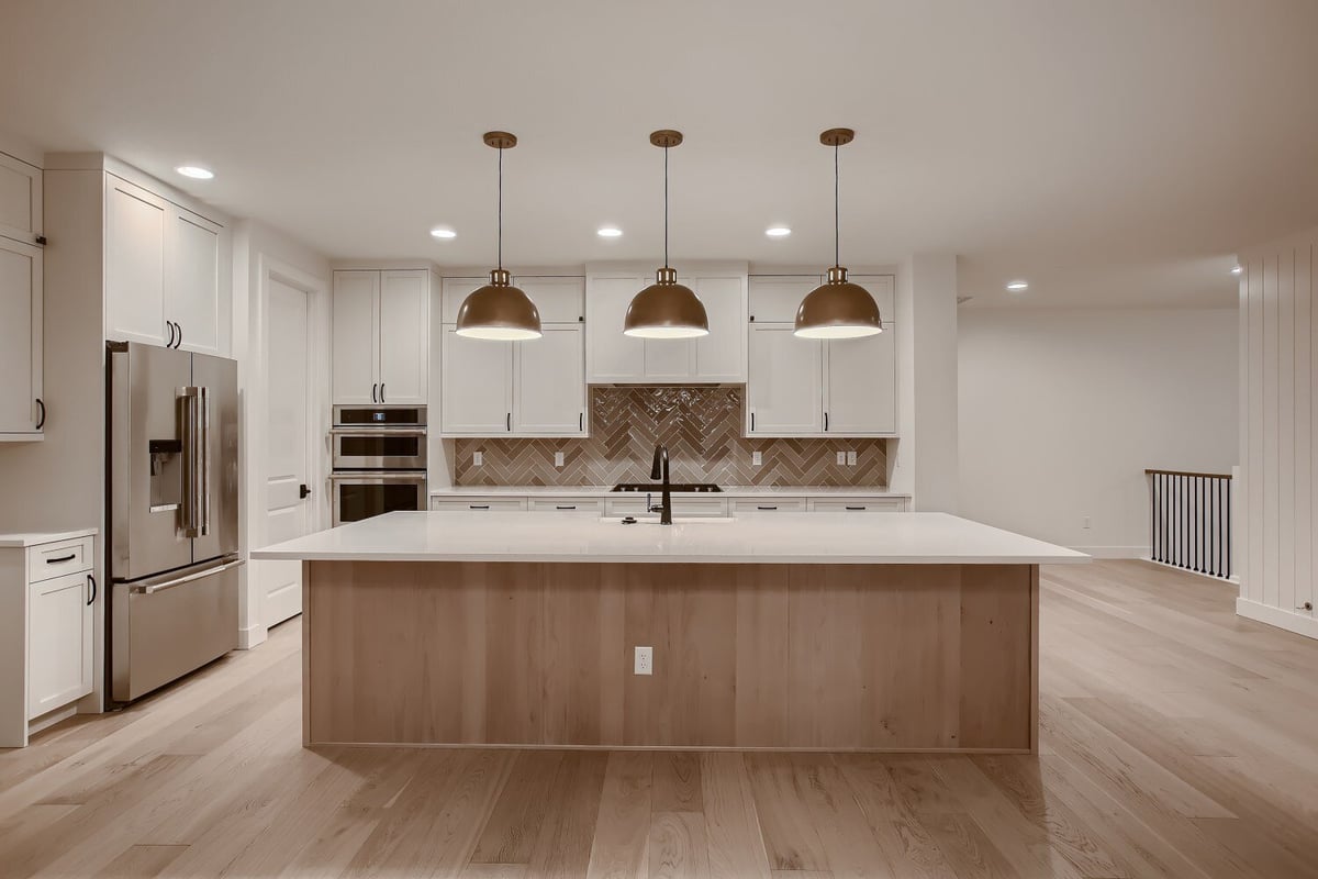 Front view of the second-floor kitchen island with dome-shaped hanging lamps in a custom home by Sheffield Homes, Arvada, CO