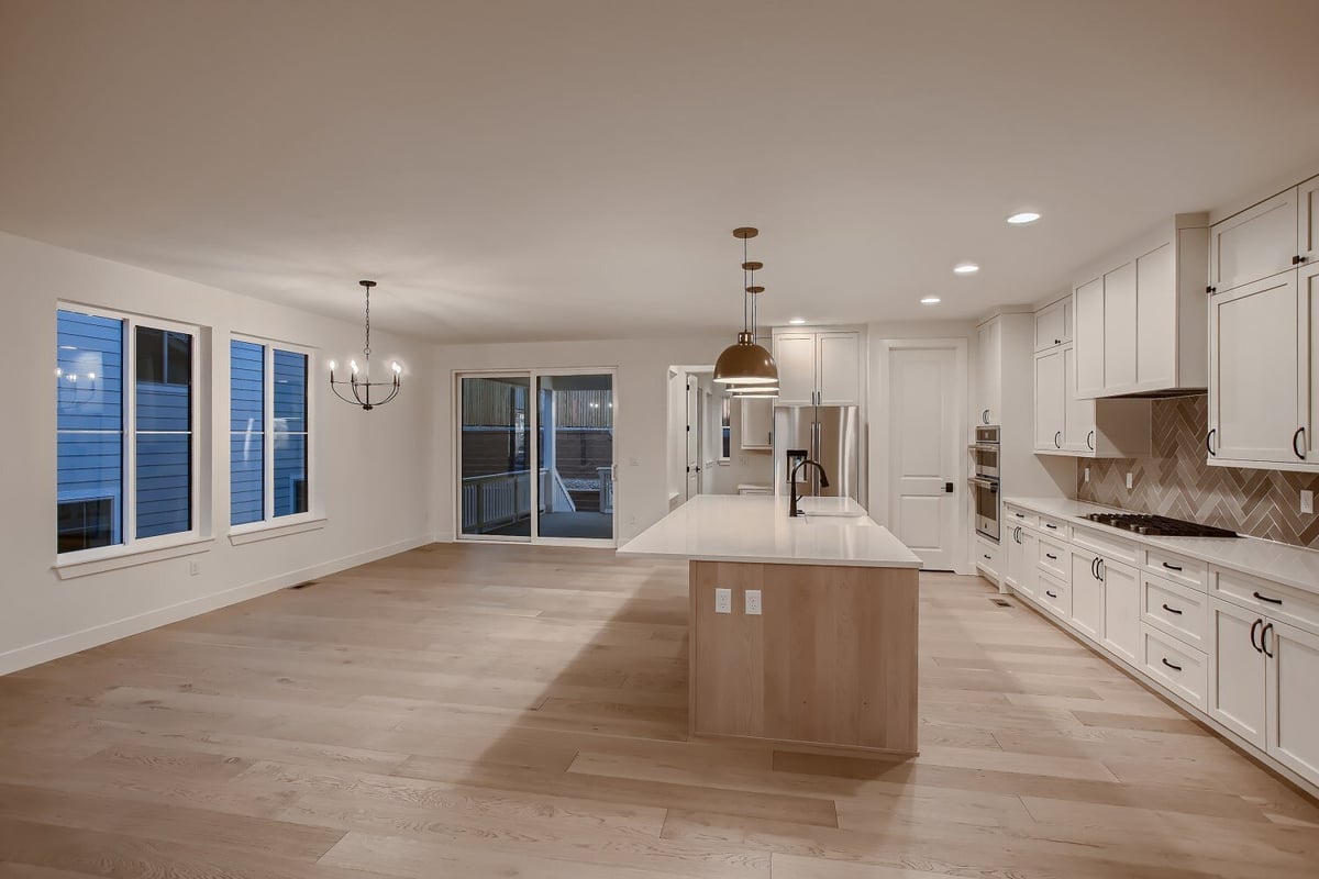 Spacious kitchen with an island, sleek cabinetry, and large windows in a custom home by Sheffield Homes in Arvada, CO