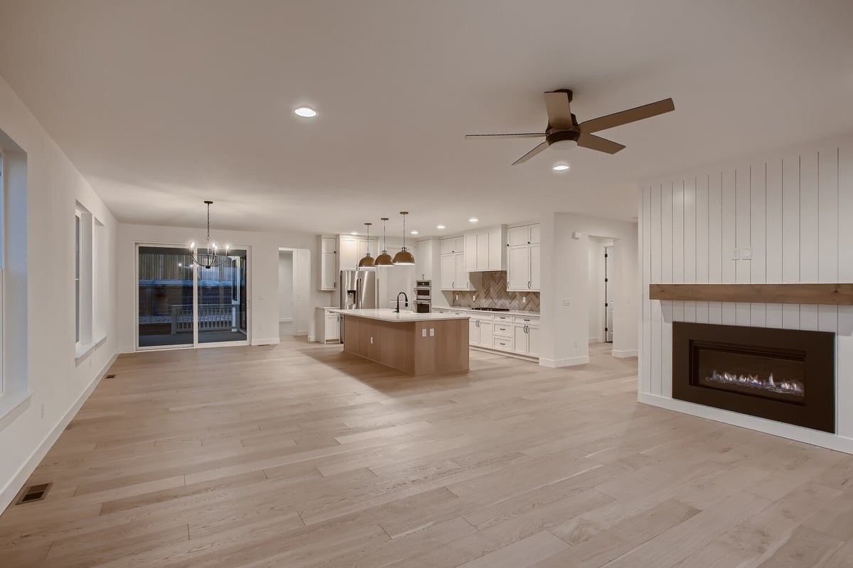 Spacious living area with fireplace and open kitchen with island and cabinetry in a custom home by Sheffield Homes, Arvada, CO