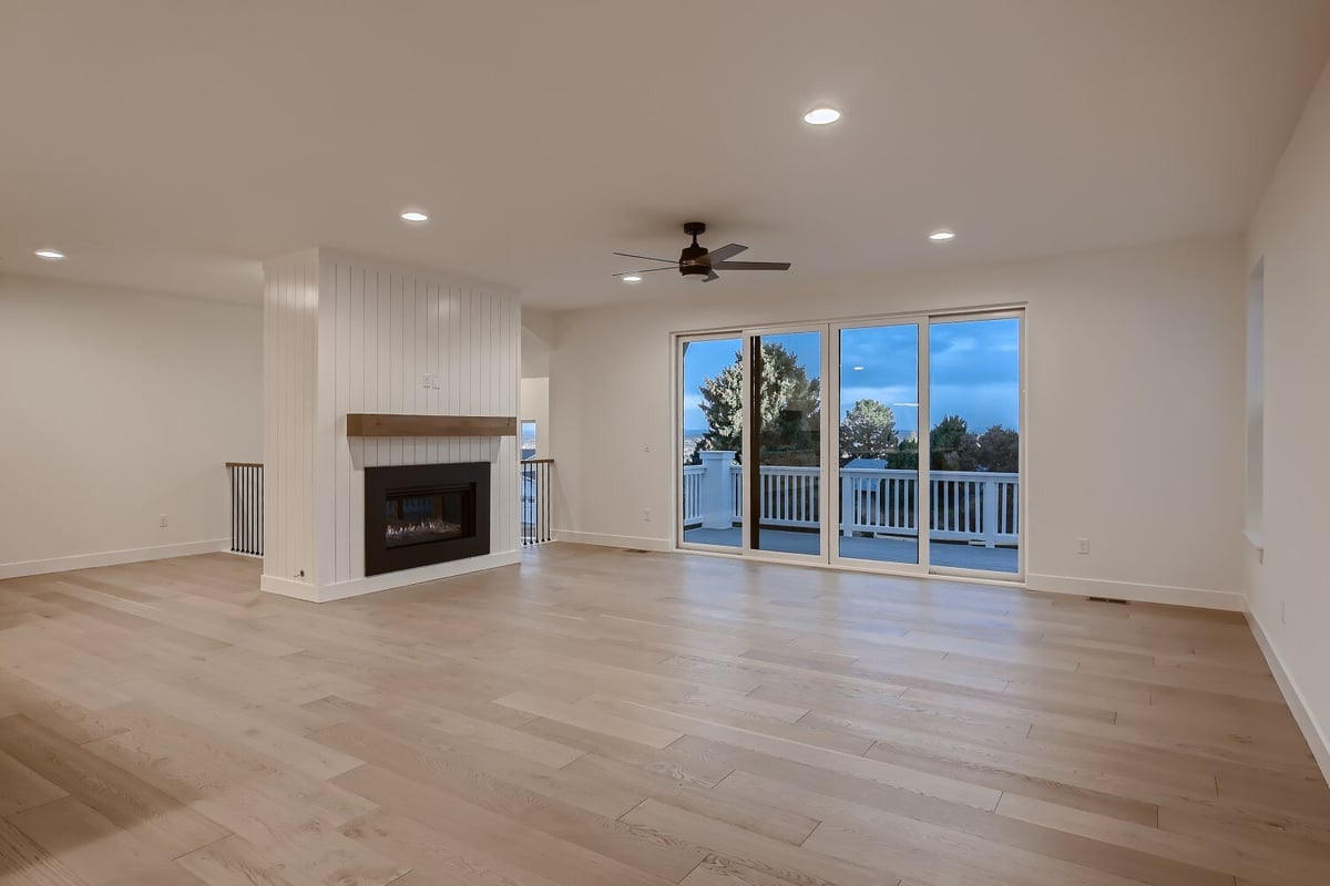 Spacious living room with ceiling fan and fireplace offering a scenic view in a custom home by Sheffield Homes in Arvada, CO