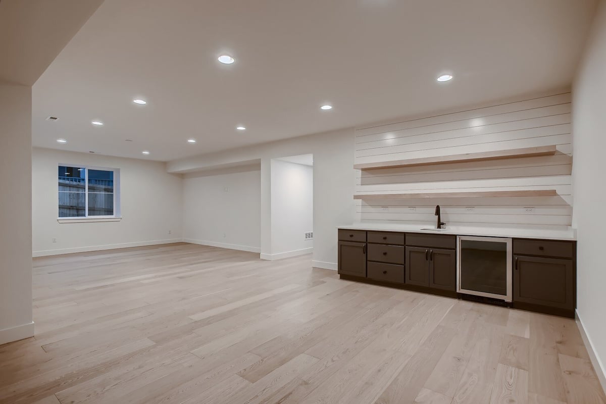 Spacious lower-level living room with a window and cabinetry wash basin in a custom home by Sheffield Homes, Arvada, CO