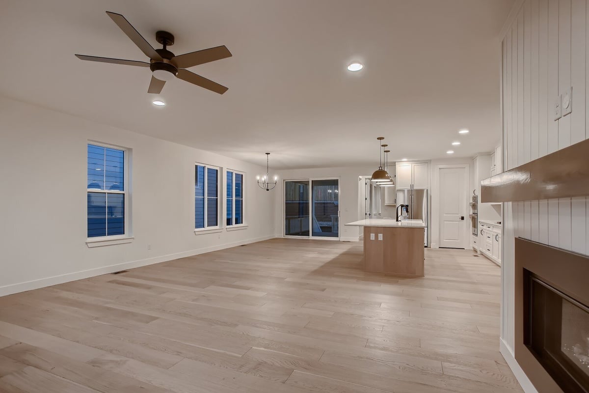 Wide shot of a spacious living area with fireplace and open kitchen in a custom home by Sheffield Homes, Arvada, CO