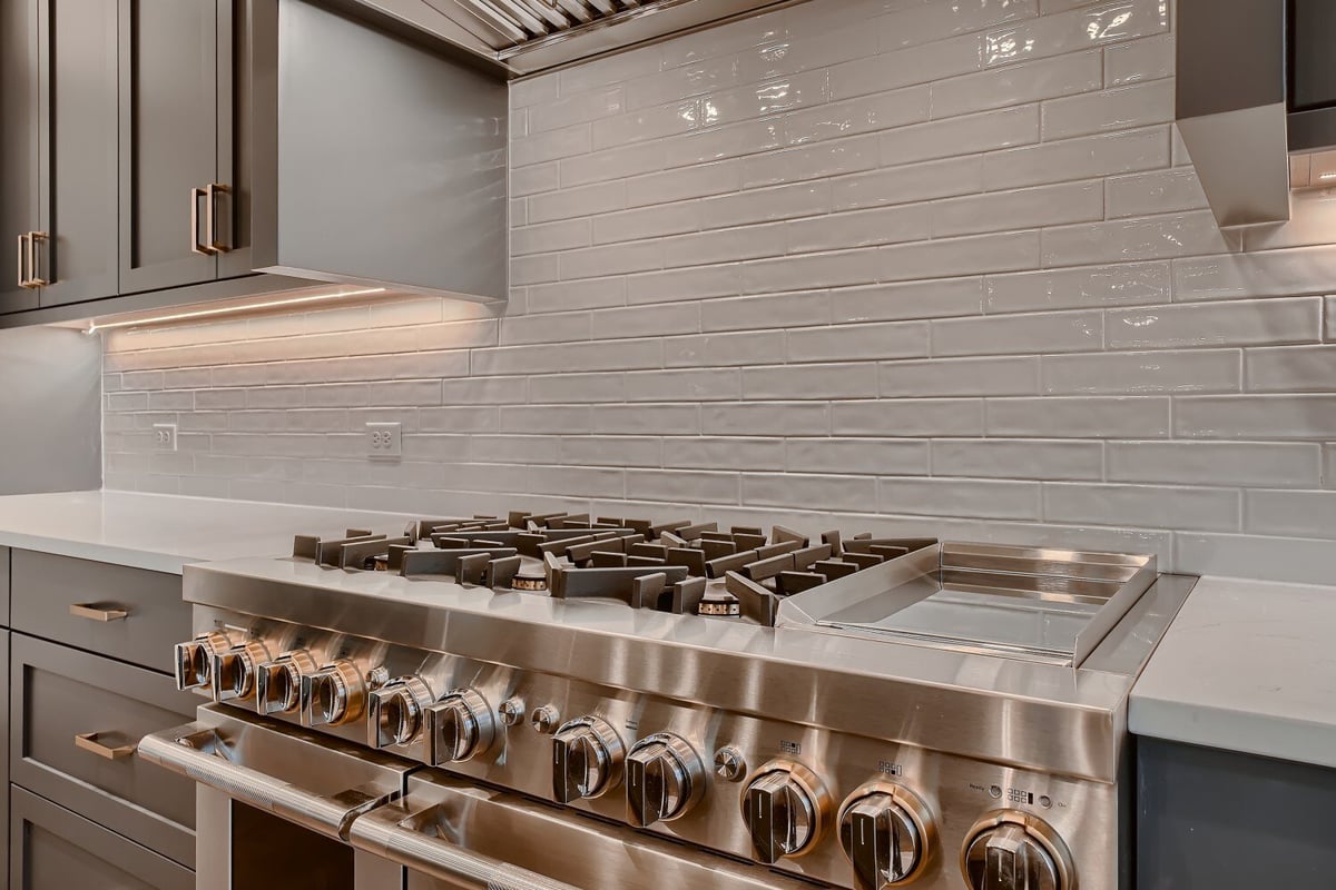 Closeup of a modern kitchen with raised stove and sleek cabinetry by Sheffield Homes in Arvada, CO