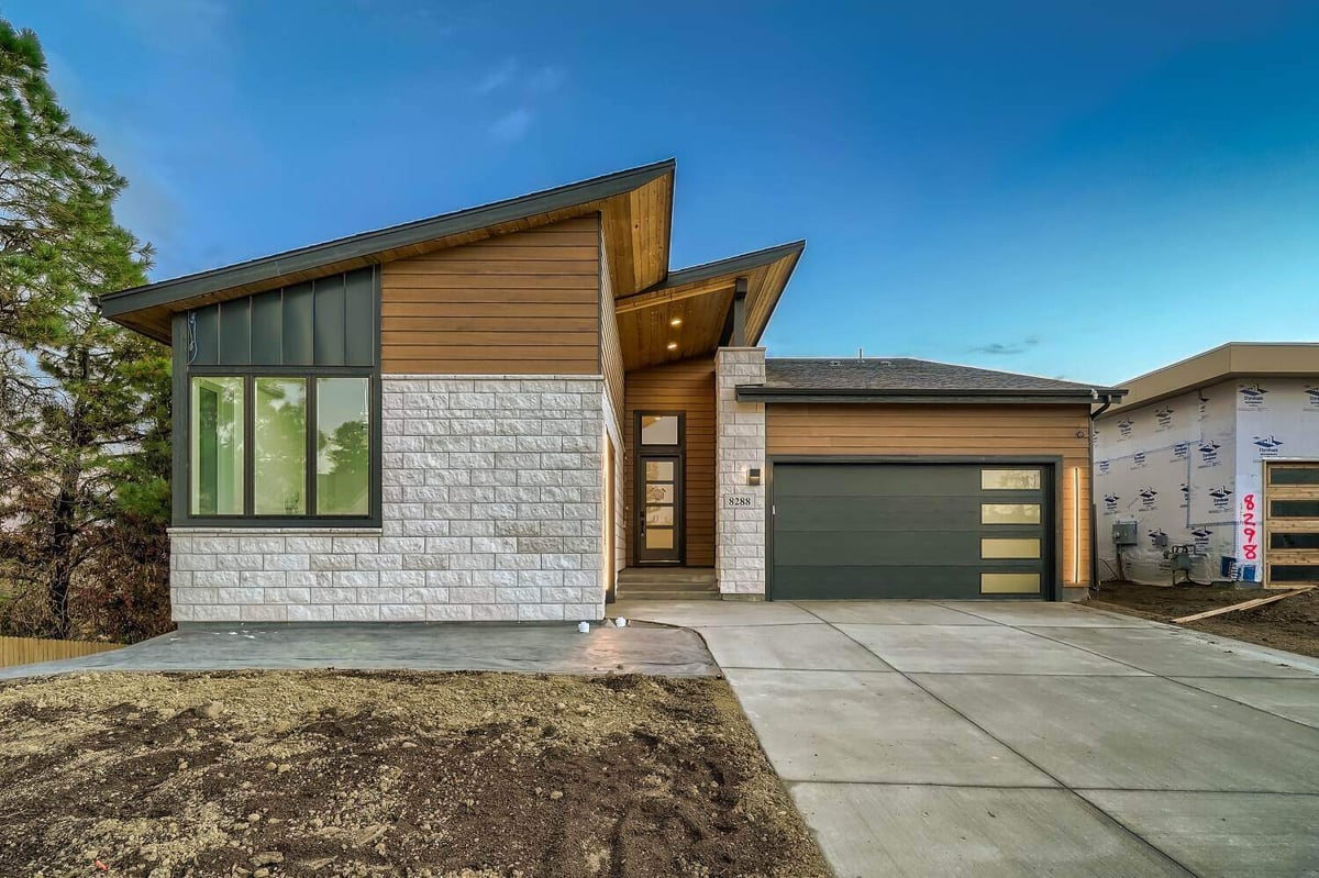 Daytime exterior front view of an elegantly constructed house by Sheffield Homes in Arvada, CO, featuring stone and wood design