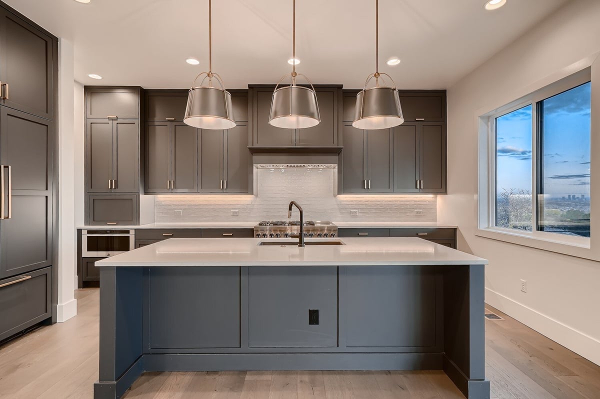 Front view of a subtle blue kitchen island with elegant lighting and sleek kitchen furniture by Sheffield Homes in Arvada, CO