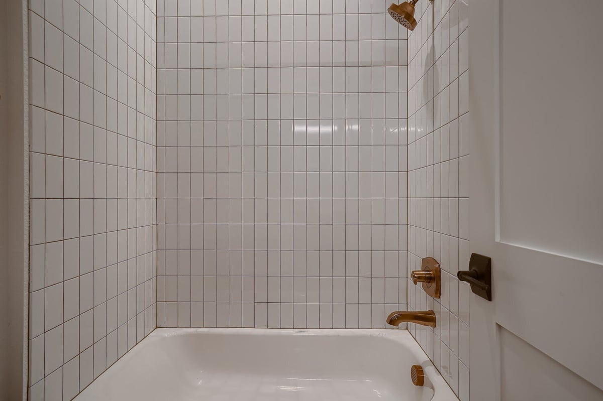 Modern bathtub in a Jack and Jill lower-level bathroom with tiled walls in a custom home by Sheffield Homes in Arvada, CO