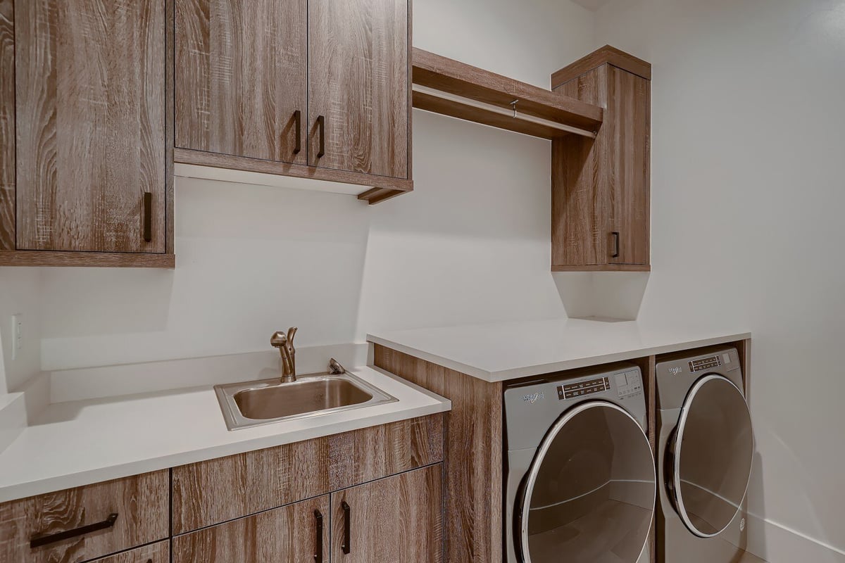 Modern laundry room with acrylic wood-design cabinetry in a house by Sheffield Homes in Arvada, CO