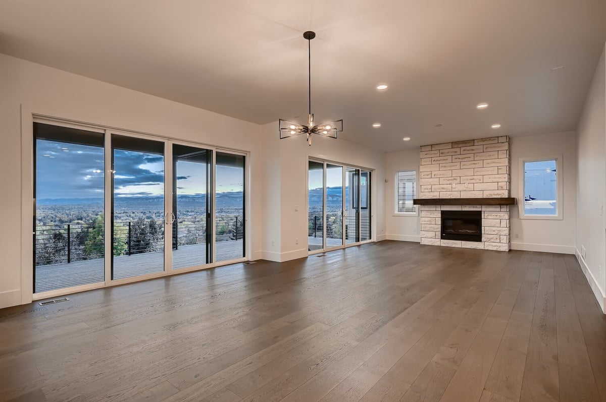 Modern living room with large sliding doors, a fireplace, and a beautiful chandelier, by Sheffield Homes in Arvada, CO