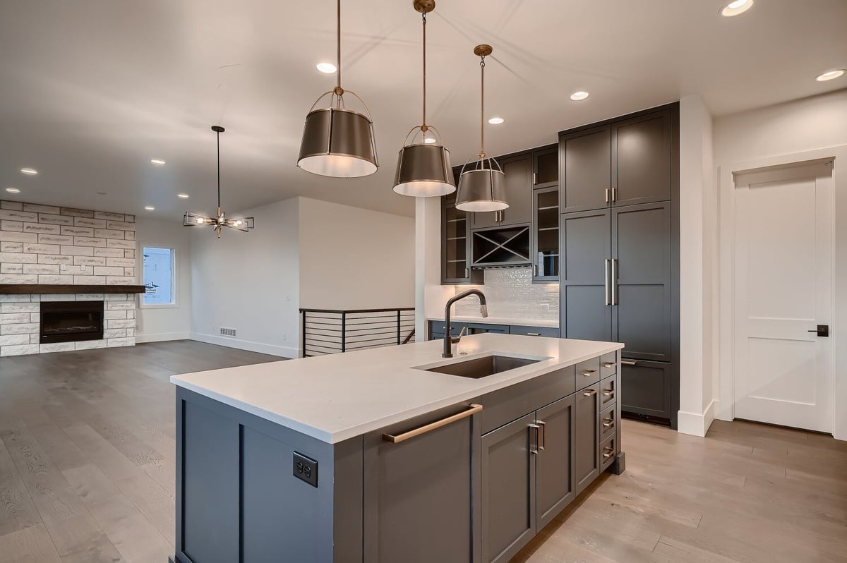 Premium kitchen island with elegant hanging lamps and sleek cabinetry by Sheffield Homes in Arvada, CO