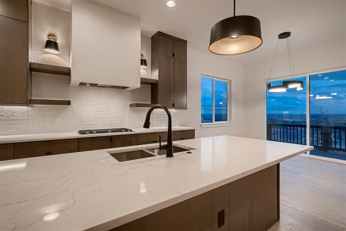 Closeup of the kitchen island with a smooth white top and wooden base in a house by Sheffield Homes in Arvada, CO