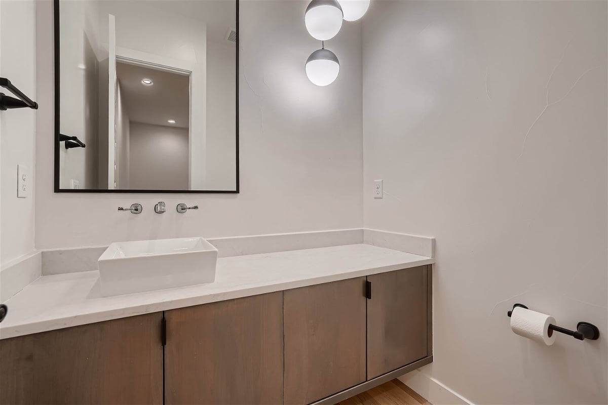 Modern powder room with a single vanity and elegant light bulbs in a custom home by Sheffield Homes in Arvada, CO