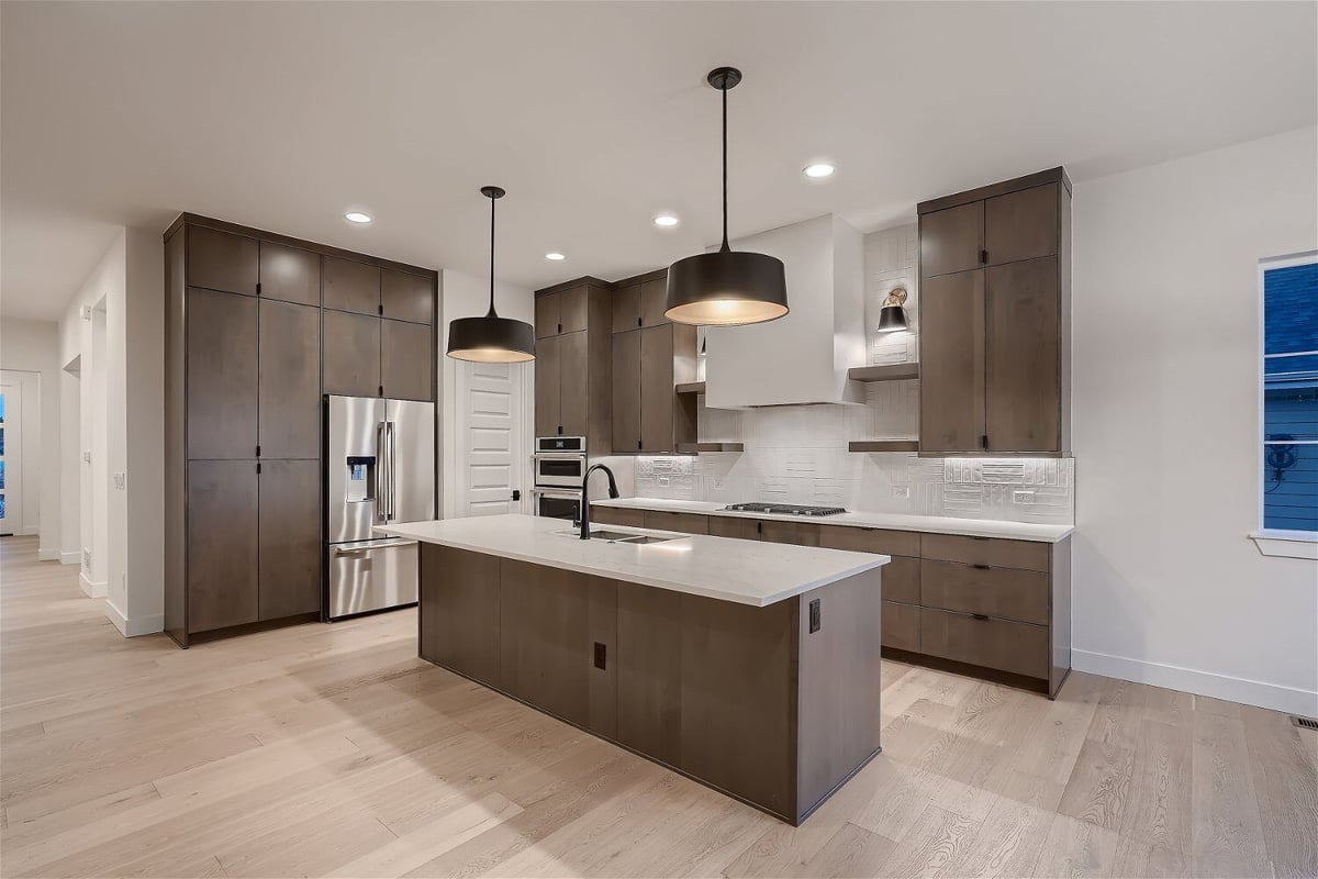 Side view of a modern kitchen with sleek wooden cabinetry and elegant lighting by Sheffield Homes in Arvada, CO