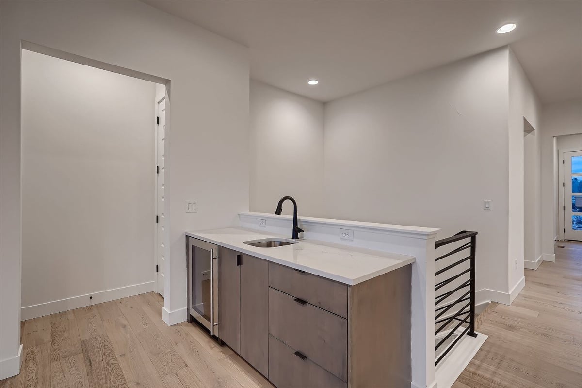 Space-efficient wetbar with a staircase and metal railing in a home by Sheffield Homes in Arvada, CO