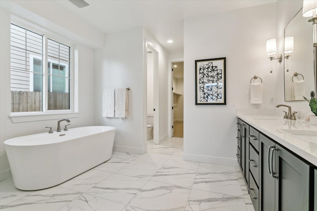 Bathroom with a freestanding bathtub and a vanity with elegant lighting in a custom home by Sheffield Homes in Arvada, CO