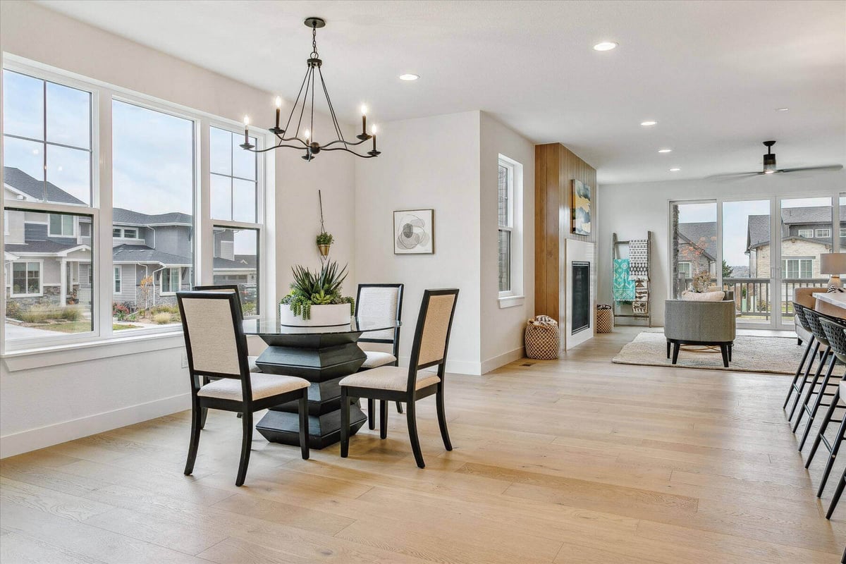 Elegant mini dining table with a candle-lit chandelier in a spacious living room by Sheffield Homes in Arvada, CO