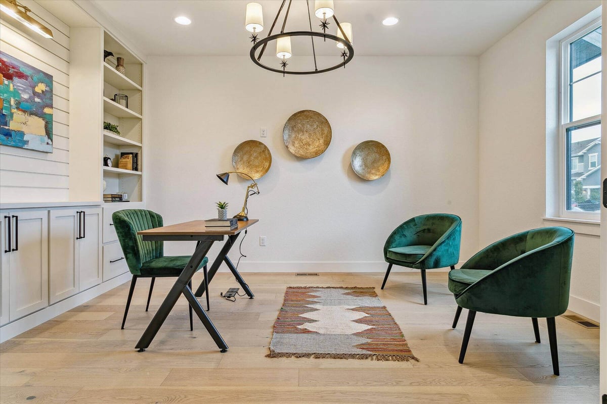 Family sitting area with stylish single sofas, a table, and an elegant chandelier by Sheffield Homes in Arvada, CO