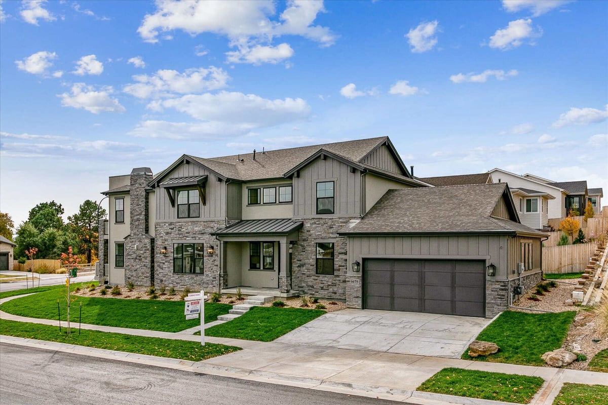 Front exterior side view of a large custom home with a lawn and garage, built by Sheffield Homes in Arvada, CO