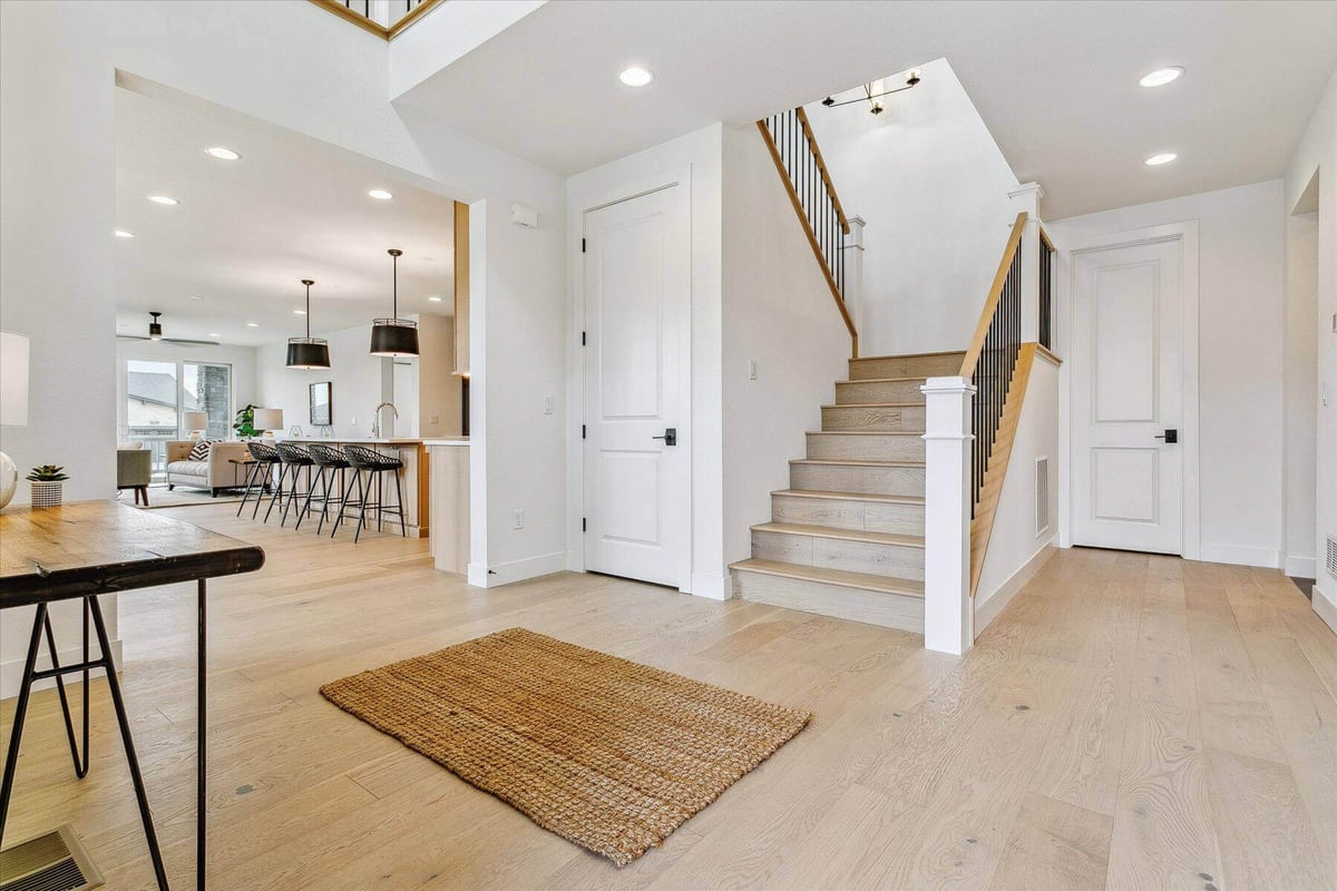 Low-level stair landing with wood and metal railings in a living room with marble flooring by Sheffield Homes in Arvada, CO