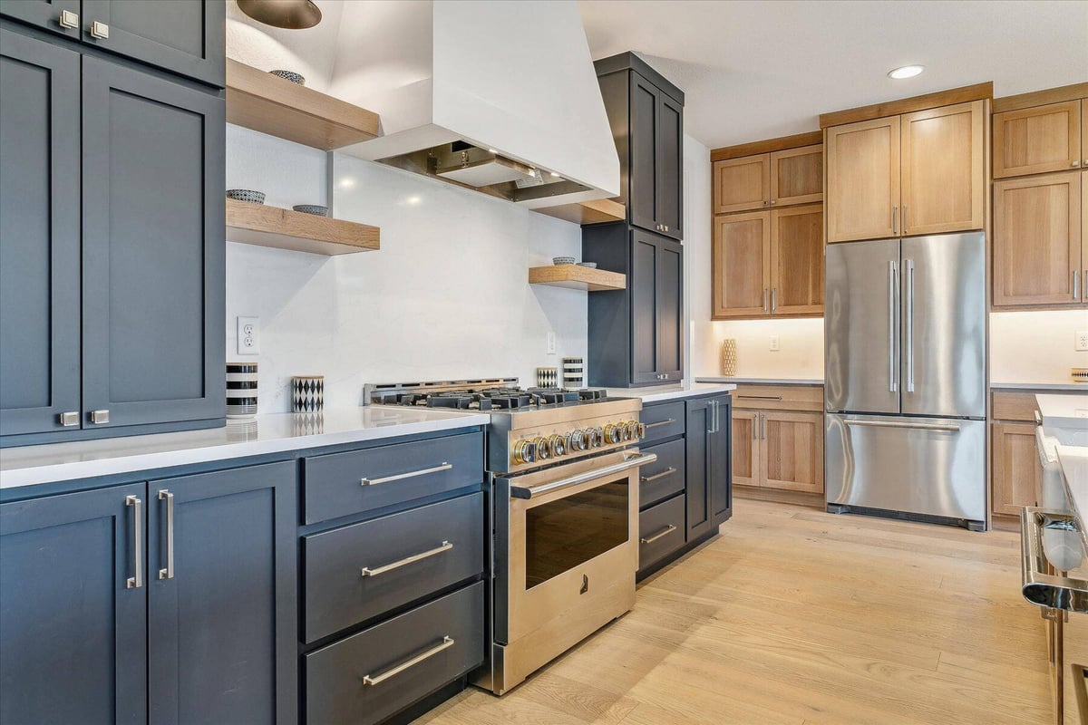 Modern kitchen with gray and wood cabinetry and stainless steel stoves in a custom home by Sheffield Homes in Arvada, CO