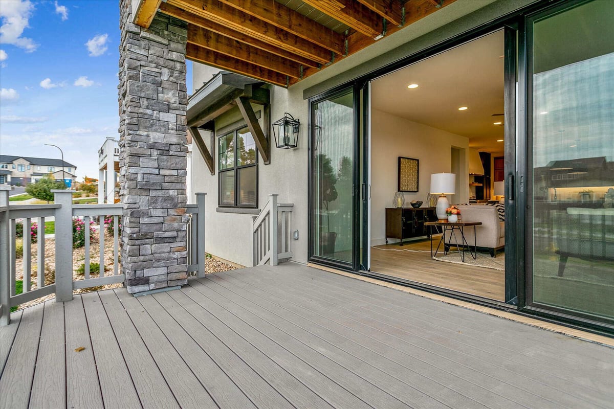 Outdoor deck adjacent to the primary living room with a stone accent pillar in a custom home by Sheffield Homes in Arvada, CO