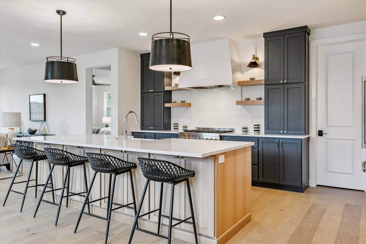 Side view of a kitchen island with a smooth white top and dining chairs in a house by Sheffield Homes in Arvada, CO