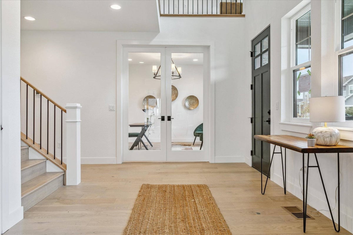 Stair with metal railings landing in a living room with marble flooring and a bamboo rug - by Sheffield Homes in Arvada, CO