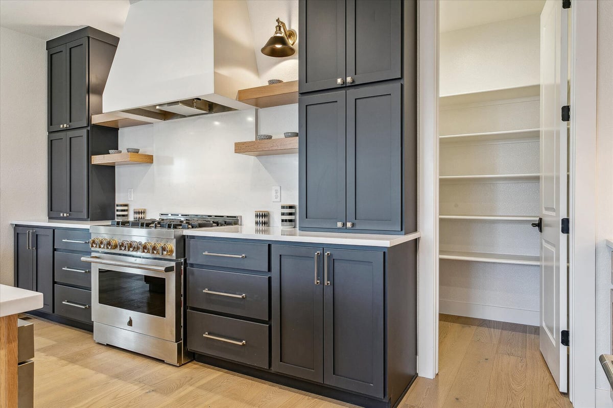 Stylish kitchen cabinetry with stove detailing and a mini dining table in the background by Sheffield Homes in Arvada, CO