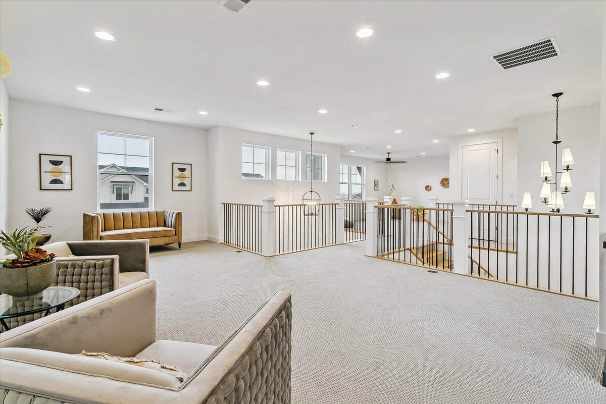 Upper-level living room with sofas, carpet flooring, and a modern foyer in a custom home by Sheffield Homes in Arvada, CO