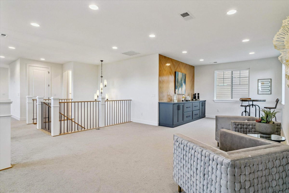 Upper-level spacious foyer with multiple sofas and carpet flooring in a custom home by Sheffield Homes in Arvada, CO