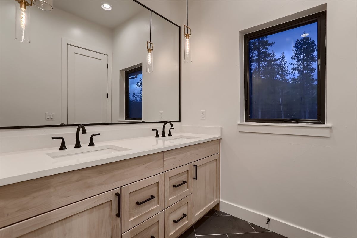 Bathroom details featuring dual black faucets and elegant lighting in a custom home by Sheffield Homes in Evergreen, CO