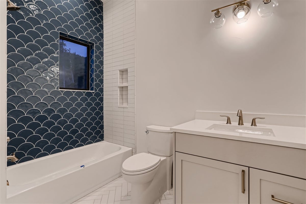 Bathroom with a single vanity, toilet seat, and built-in bathtub with a featured wall - by Sheffield Homes in Evergreen, CO