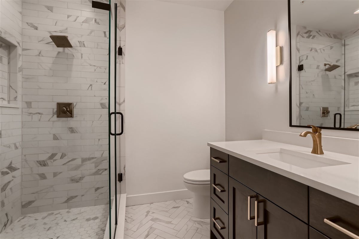 Bathroom with an elegant shower room, vanity, and toilet seat in a custom home by Sheffield Homes in Evergreen, CO